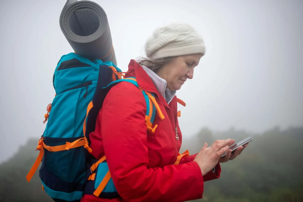 Hiker checking phone and writing route plan before hike